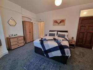 a bedroom with a bed with a blue and white blanket at Spacious Homey Gem Minutes to the Beach w/Garden in Seascale