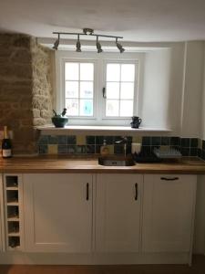 a kitchen with a counter top and two windows at Lovely listed cottage in old centre with garden. in Oundle