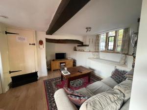 ein Wohnzimmer mit einem Sofa und einem Tisch in der Unterkunft Lovely listed cottage in old centre with garden. in Oundle