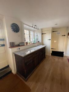 a kitchen with a large counter and a clock on the wall at Lovely listed cottage in old centre with garden. in Oundle