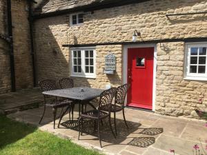 a table and chairs in front of a building with a red door at Lovely listed cottage in old centre with garden. in Oundle