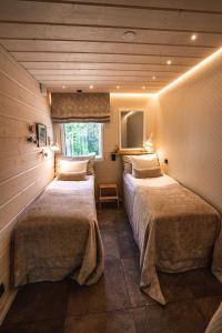 two beds in a room with wooden walls at Villa Pöylikki in Rovaniemi