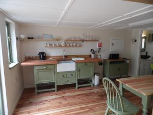 Newchurch Nook في Newchurch: مطبخ مع دواليب خضراء وطاولة خشبية