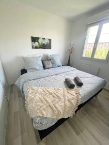 een slaapkamer met een bed met twee slippers erop bij Agréable et grande maison avec parking + jardin in Villeurbanne
