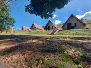 a house on top of a grassy hill at Pousada e Pesque e Pague Vista Alegre in Paty do Alferes