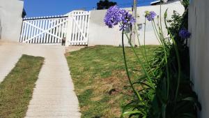 a white fence and purple flowers next to a sidewalk at Apê Bella Vista Campos in Campos do Jordão