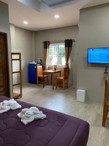 Zimmer mit einem Bett, einem Tisch und einem TV in der Unterkunft Greathill Gardenhome Resort Chomthong-Chiangmai in Chom Thong