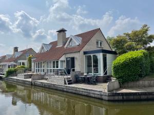 a house on the side of a river at Watervilla de Rietzanger by Droomvilla in Langweer