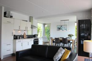 a living room with a couch and a kitchen at Watervilla de Rietzanger by Droomvilla in Langweer