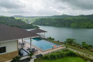una piscina con vistas al lago en Lake Arches by StayVista - Lakeside villa with Infinity pool, Gazebo & Modern Greek interiors, en Igatpuri