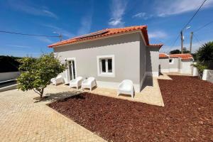 una casa bianca con quattro sedie bianche davanti di New Beach House near main street close PraiaGrande a Colares