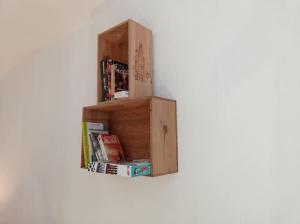une étagère en bois avec des livres sur un mur dans l'établissement Appartement le bar du JURA, à Saint-Claude