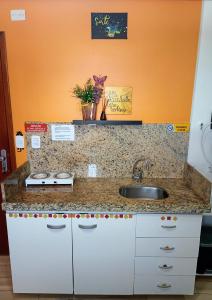 um balcão de cozinha com um lavatório e uma parede laranja em Flat pé na areia Tambaú em João Pessoa