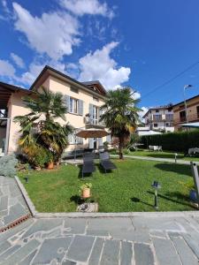 a yard with chairs and palm trees in front of a building at B & B Ametista Bergamo in Ponteranica