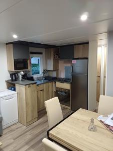 加斯泰Mobil-home Camping Siblu La Reserve ****的厨房配有木制橱柜和桌椅
