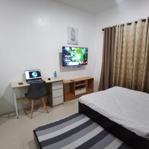 a bedroom with a bed and a desk with a television at Affordable Condo w/ Shower Heater and Wi-Fi in Minglanilla