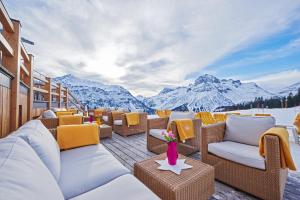 una terraza con sofás, mesas y montañas en Hotel Mohnenfluh, en Lech am Arlberg