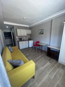 a living room with a yellow couch and a kitchen at Imperial Apart in İçmeler