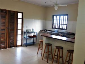 a kitchen with a counter and stools in it at Casinha Mar e Sol Boiçucanga in São Sebastião