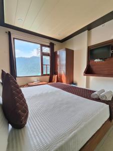 um quarto com uma cama grande e uma janela grande em The Panda em Dharamshala