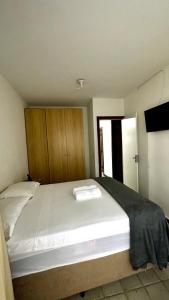 a bedroom with a large white bed with wooden cabinets at Apartamento inteiro frente ao mar de ondina in Salvador