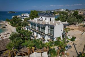 an aerial view of a white building with palm trees at HOTEL DENOEL in Ksamil