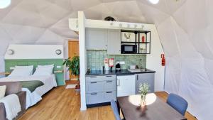 um pequeno quarto com uma cama e uma cozinha com uma mesa em Vi Naturae Glamping em Fajã da Ovelha