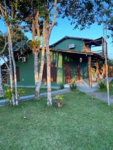 a green house with trees in front of it at Casa Lua Cheia in Praia do Espelho
