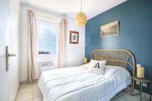 a bedroom with blue walls and a bed with a pillow at Le balcon de Jersey - face à la mer in Saint-Jean-de-la-Rivière