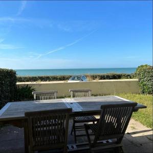 a wooden table with two chairs and the ocean at Le balcon de Jersey - face à la mer in Saint-Jean-de-la-Rivière