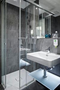 W łazience znajduje się umywalka i przeszklony prysznic. w obiekcie Hotel du Commerce w Bazylei