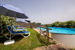 a pair of chairs and an umbrella next to a swimming pool at La pieve - Gerani in Pereta