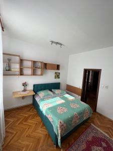 een slaapkamer met een groen bed en een houten vloer bij Balcescu Alina's apartament in Sibiu