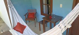 a hammock with a table and a chair in a room at Canto do Sabiá Caraíva in Caraíva
