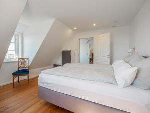 ein weißes Schlafzimmer mit einem großen Bett und einem blauen Stuhl in der Unterkunft Emmas Hus in Pellworm