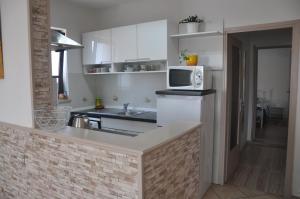 uma cozinha com armários brancos, um lavatório e um micro-ondas em Apartman Mirna em Rovinj
