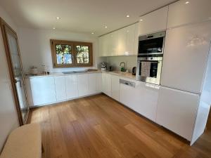 a kitchen with white appliances and a wooden floor at Chalet Rose Bay in Leysin