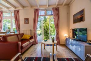 a living room with a couch and a tv at Appartementen BuitenWedde Westerwolde in Wedde
