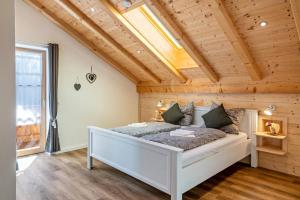 ein Schlafzimmer mit einem weißen Bett in einem Zimmer mit Holzdecken in der Unterkunft Wohnung Brauneck in Gaißach