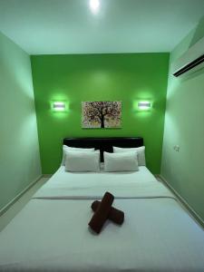 a green bedroom with a bed with a cross on it at Sandy Beach Resort By Casa Loma in Pantai Cenang