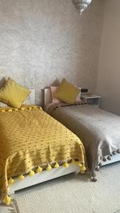 a bedroom with two beds with yellow and pink pillows at Logement moderne et neuf entièrement équipé in Fez
