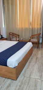 ZirakpurにあるHotel Holiday Vibeのベッドルーム1室(大型ベッド1台、椅子2脚付)