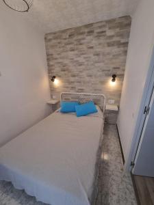 アリカンテにあるApartamentos Alicanteの小さなベッドルーム(青い枕のベッド付)