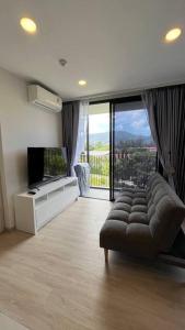 a living room with a couch and a large window at Laguna Sky Park Corner 1 Bedroom in Bang Tao Beach