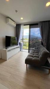 a living room with a couch and a large window at Laguna Sky Park Corner 1 Bedroom in Bang Tao Beach +30 photos