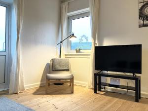 One Bedroom Apartment In Odense, Middelfartvej 259 في أودنسه: غرفة معيشة مع كرسي وتلفزيون بشاشة مسطحة