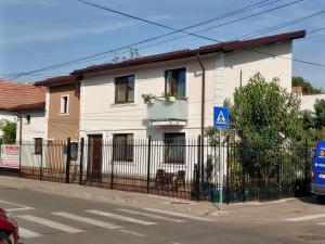 a white house with a fence on a street at Casa Petcu in Craiova