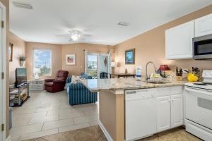 a kitchen with white appliances and a living room at Grande Caribbean 326 in Orange Beach