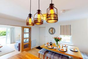 a dining room with a table and three lights at Croyde Secret Garden in Croyde