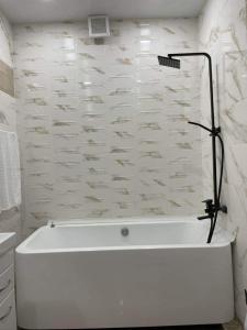 a white bath tub in a bathroom with white tiles at My Sweet Home In Rustavi sity 2 in Rustavi